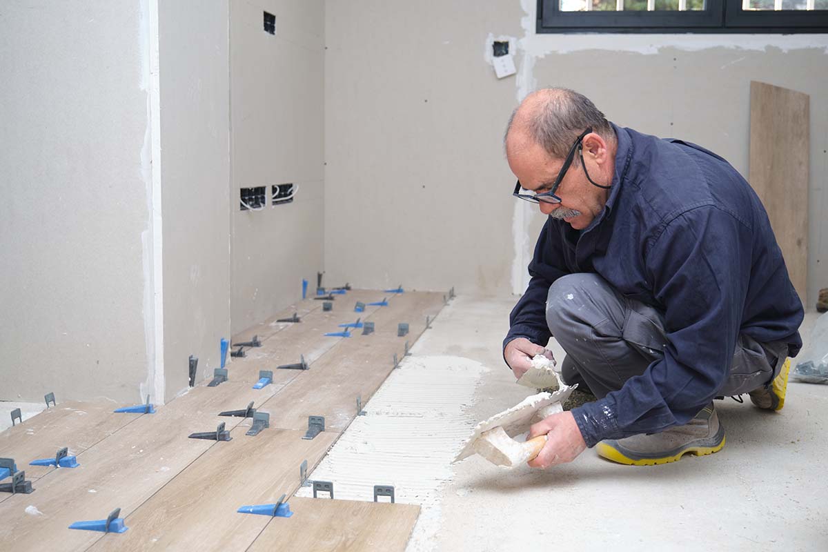 kitchen fitter laying tiles on the floor of a kitchen