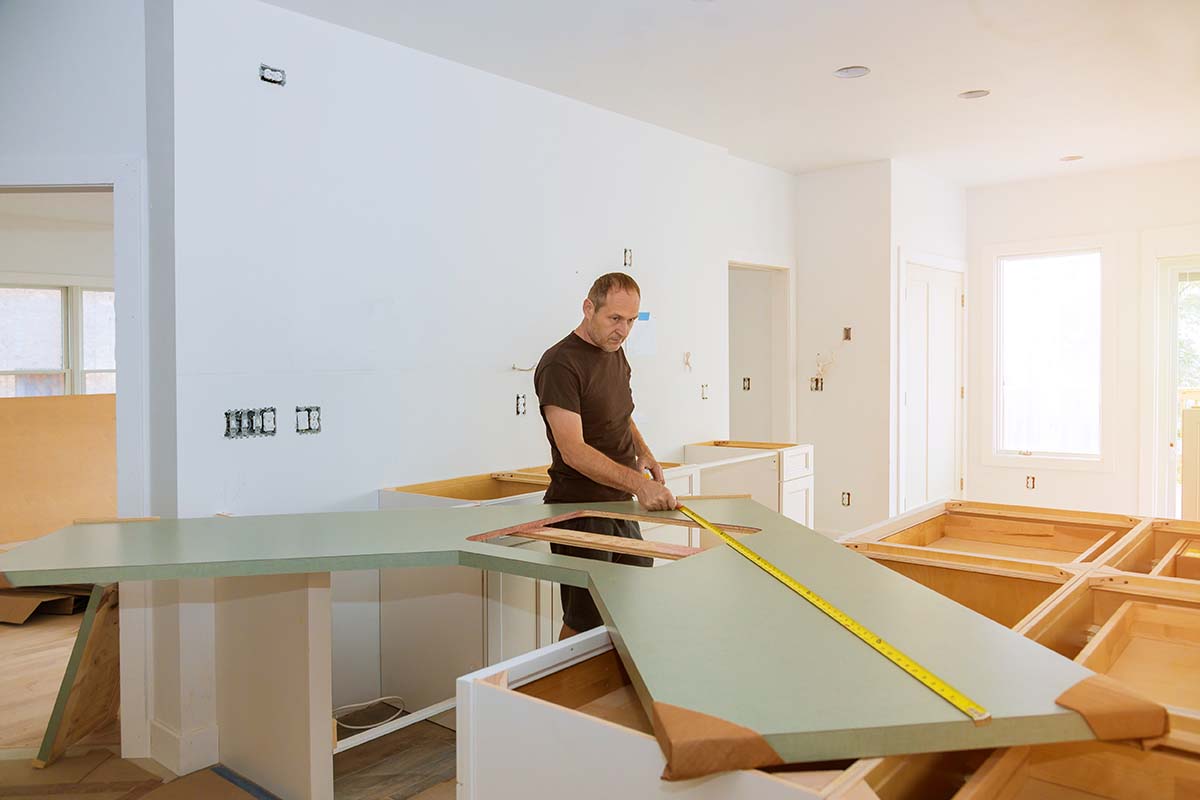 a man measuring and fitting a kitchen worktop