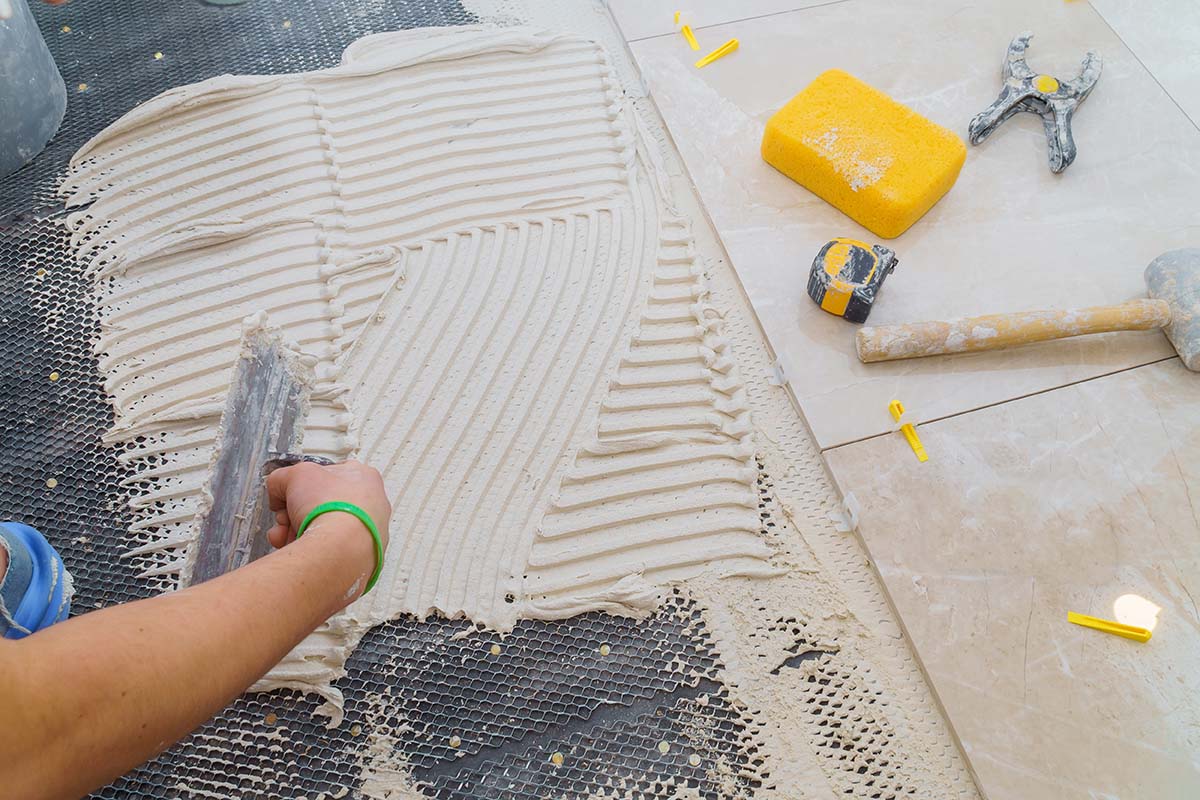 professional laying adhesive before installing kitchen floor tiles