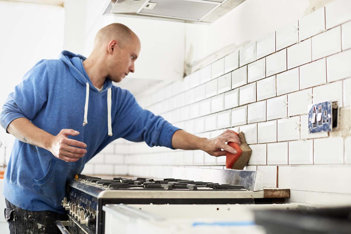 man clearing grout on tiles