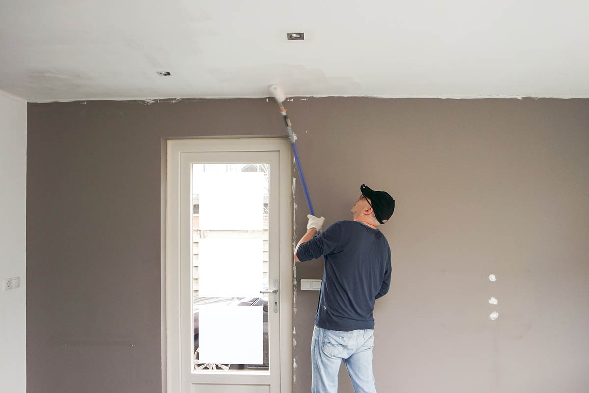 a man painting the ceiling of his bedroom