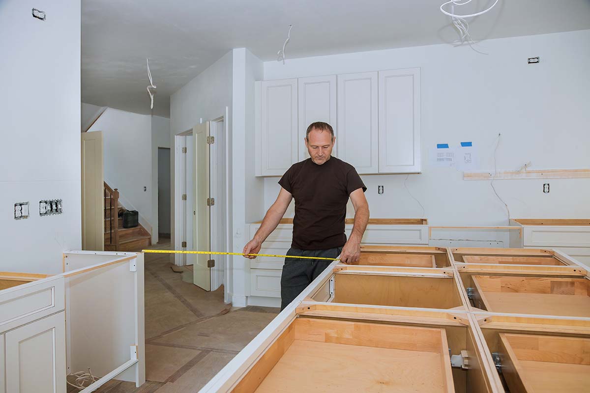 man measuring distances between kitchen worktop and other furniture
