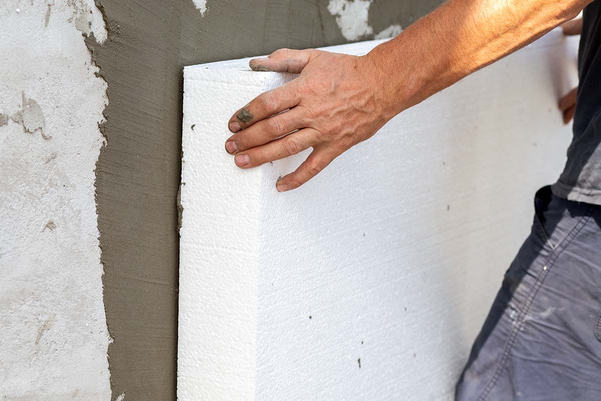worker waterproofing cellar walls with insulation