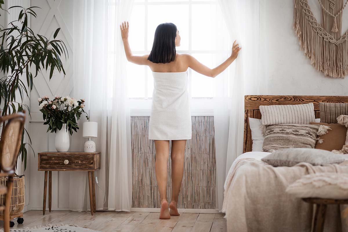 woman looking through window in her small bedroom